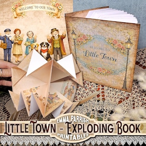 May include: A square book with a vintage-style cover featuring the text Welcome to Little Town, notes kept, stories shared, moments saved, and an exploding paper craft insert with illustrations of townspeople and dogs in a sepia-toned palette.