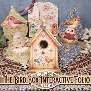 May include: A collection of decorative bird-themed paper crafts. Includes a birdhouse, bird cutouts, and a teacup with an egg. The birdhouse is painted with blue and orange birds. The text "The Bird Box Interactive Folio Printables" is visible.