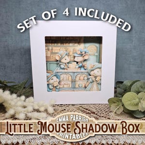 Może przedstawiać: Biała, oprawiona skrzynka cieni z szczegółową ilustracją czterech myszy w otoczeniu sklepu. Myszki ubrane są w niebieskie i beżowe stroje. U góry widnieje napis "SET OF 4 INCLUDED". Na dole ramy widnieje napis "Little Mouse Shadow Box Printables".