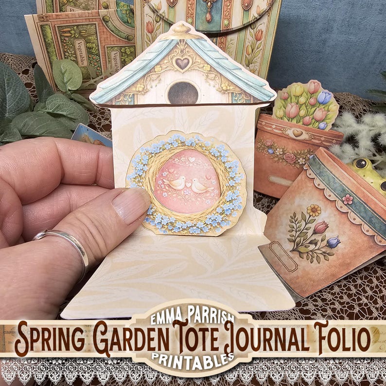 May include: A paper craft journal folio with a spring garden theme. The design includes a birdhouse, flower pots, and a wreath with two doves. The text "Spring Garden Tote Journal Folio Printables" is visible.