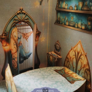 Puede incluir: Diario desplegable imprimible titulado "Blue Fairy Hideaway" con un tutorial incluido. El diario presenta una habitaci&oacute;n de hadas caprichosa con un vestido azul colgado en una puerta, una mesa con sillas, una cama y un estante con botellas.