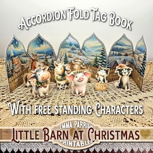 May include: An accordion-fold tag book with a winter scene backdrop and free-standing animal characters. The book features illustrations of a cow, goat, pig, cat, and dog, all adorned with festive details. The text on the book reads "Accordion Fold Tag Book" and "Little Barn at Christmas."