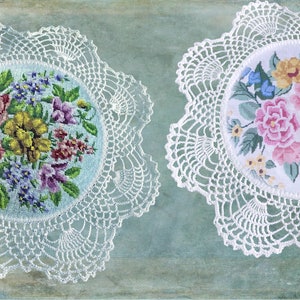 May include: Two white crocheted doilies with embroidered floral designs. The doilies feature a variety of colorful flowers, including pink, yellow, and blue.