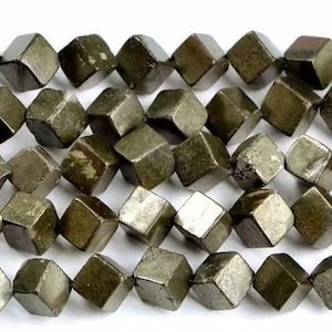 Könnte beinhalten: Nahaufnahme von Pyrit-Perlen in Würfelform. Die Perlen haben eine metallische, gedämpfte Goldfarbe mit Texturvariationen. Sie sind aufgefädelt und eignen sich für Schmuckherstellung oder Bastelarbeiten.