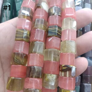 May include: Strands of cube-shaped beads in shades of pink, brown, and yellow. The beads are strung together, creating a textured and colorful pattern. The text "#1" is visible in the upper left corner.