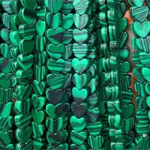 May include: A strand of green malachite heart-shaped beads. The beads have a striated pattern and are strung together on a clear thread.