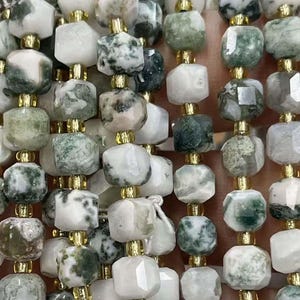 Puede incluir: Una hebra de cuentas de ágata verde y blanca con separadores dorados. Las cuentas son facetadas y tienen una forma natural irregular.
