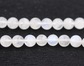 May include: A strand of white moonstone beads. The beads are round and smooth, with a subtle iridescent sheen.