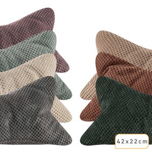 Könnte beinhalten: Eine Sammlung von sternförmigen Kissen mit einer strukturierten, genoppten Oberfläche in verschiedenen Farben wie Mauve, Salbeigrün, Beige, Anthrazit, Hellbraun, Braun und Dunkelgrün. Jedes Kissen misst laut Text 42 x 22 cm.