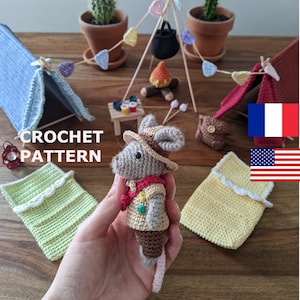 以下が含まれることがあります： ミニチュアキャンプシーンの編み物パターン。帽子とベストを着た編み物のネズミ、2つのテント、キャンプファイヤー、ミニチュア寝袋が含まれています。「CROCHET PATTERN」の文字が見えます。