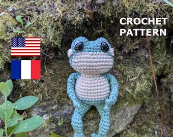 May include: Crochet pattern for a green and beige frog amigurumi. The frog is sitting on a mossy rock with the text "CROCHET PATTERN" above it.