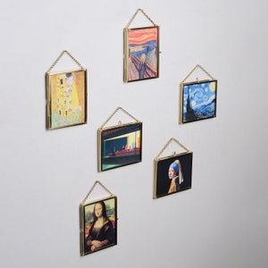 May include: Five framed art prints hanging on a white wall. The prints feature famous paintings including The Kiss, The Scream, Starry Night, The Night Cafe, and Girl with a Pearl Earring.