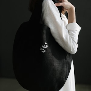 a woman in a white dress holding a black handbag