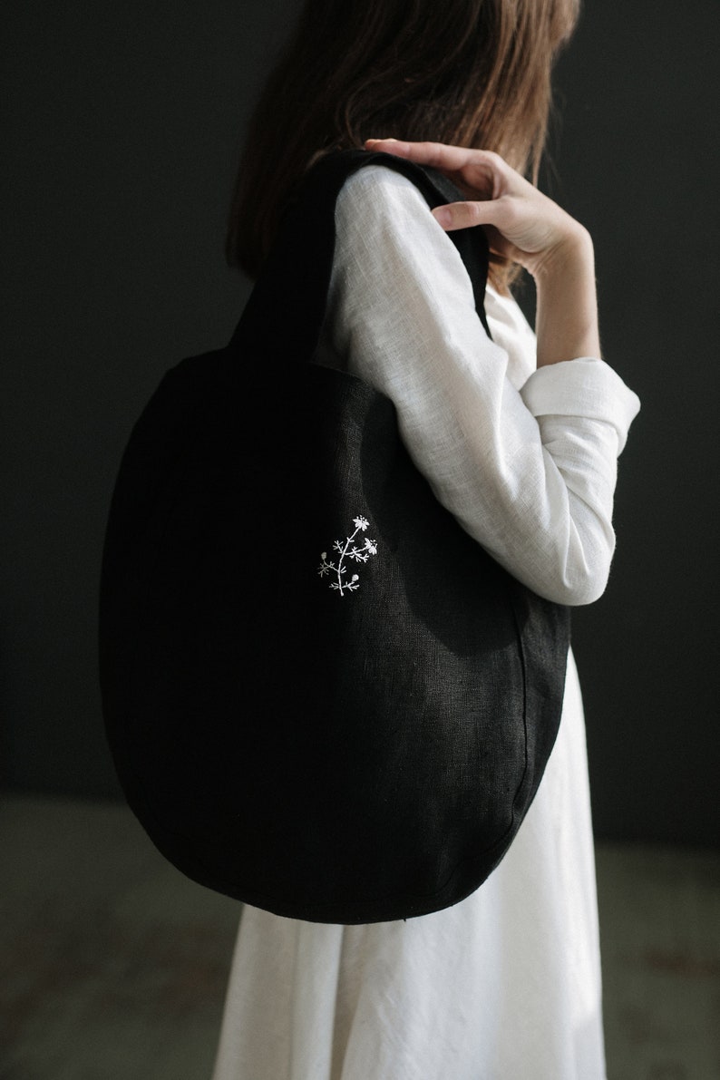 a woman in a white dress holding a black handbag