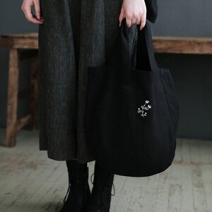 a woman holding a black bag on a wooden floor