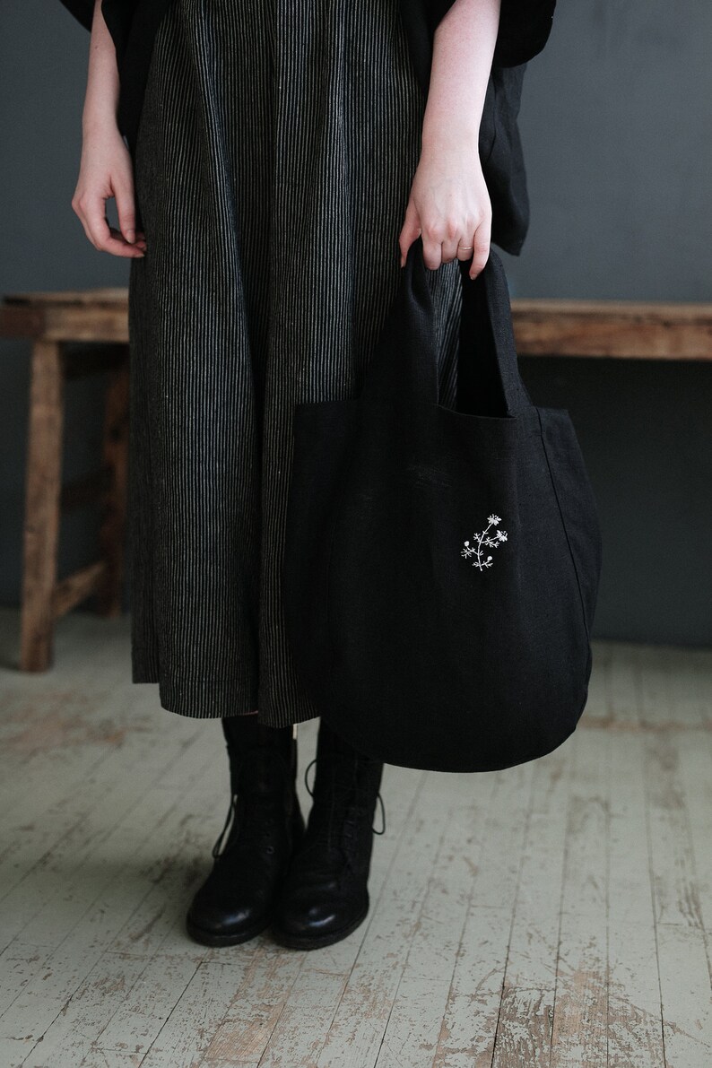 a woman holding a black bag on a wooden floor