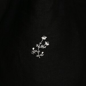 a black bag with a white flower embroidered on it