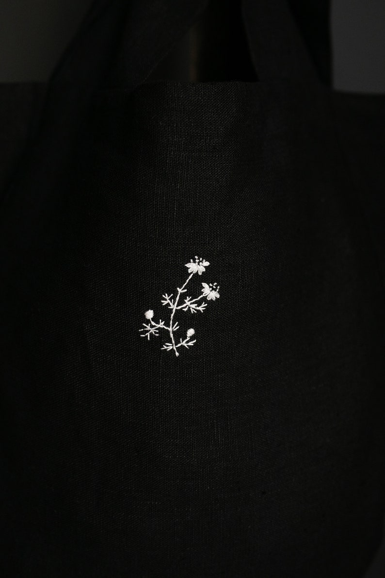 a black bag with a white flower embroidered on it