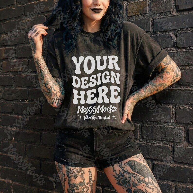 May include: Black t-shirt with the text "YOUR DESIGN HERE" in a white, retro font. The shirt also features the "MoxxyMocks" logo and "Vibes That Standout" text. The model is wearing black shorts and has tattoos on their arms and legs.