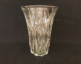 Op de afbeelding: Een heldere glazen vaas met een geometrisch patroon. De vaas heeft een brede opening en een smalle basis.