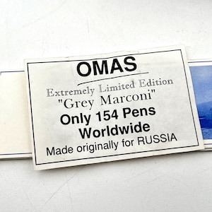 Puede incluir: Primer plano de una tarjeta rectangular blanca con la palabra "OMAS" en la parte superior. La tarjeta dice "Edici&oacute;n Extremadamente Limitada 'Grey Marconi' Solo 154 Plumas en Todo el Mundo Hecho originalmente para RUSIA."