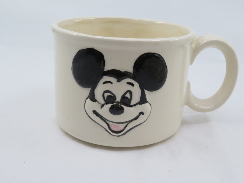 May include: White ceramic mug with a black and white image of Mickey Mouse's face.
