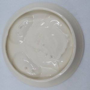 May include: White ceramic plate with a raised, textured design on the bottom. The plate has a smooth, glossy finish.