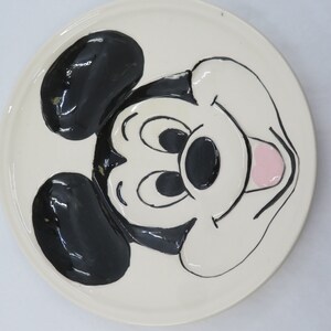 May include: White ceramic plate with a black and white cartoon image of Mickey Mouse. Mickey Mouse is smiling with his tongue sticking out.