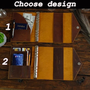May include: Two open leather binders, each with a different interior design. One has a pocket with a pen, passport, and cash. The other has a phone, cards, and pencils. The text "Choose design" is at the top.