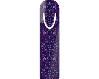 May include: A purple bookmark with a white curved top and a patterned design in shades of purple and pink. The bookmark has a rounded top and a white, U-shaped element for marking pages. The design features abstract shapes.