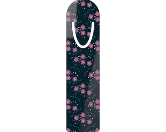 May include: A floral bookmark with a dark blue background and a pattern of pink flowers and green leaves. The bookmark has a curved top with a white loop for easy placement in a book.