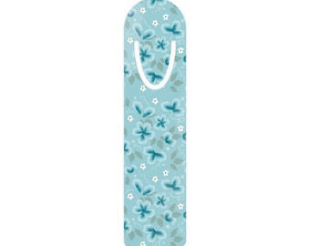 May include: A rectangular bookmark with a rounded top, featuring a light blue background decorated with a pattern of teal flowers, small white blossoms, and pale green leaves. A white U-shaped cutout is positioned near the top of the bookmark.