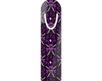 May include: A decorative bookmark with a dark purple background and a repeating floral pattern in shades of purple and green. The bookmark has a white, U-shaped top.