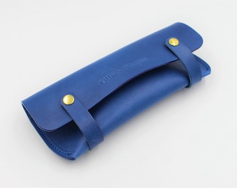 May include: A blue leather case for sunglasses with gold metal snaps and the text "Ollies Shades" embossed on the front.