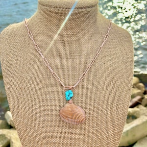 Pu&ograve; includere: Una collana con catena in oro rosa con una pietra turchese e un ciondolo a forma di conchiglia.