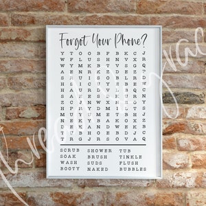 Puede incluir: Una impresi&oacute;n enmarcada en blanco con el texto "Forgot Your Phone?" y un crucigrama con las palabras "Scrub, Shower, Tub, Soak, Brush, Tinkle, Wash, Suds, Flush, Booty, Naked, Bubbles" impresas debajo del crucigrama.