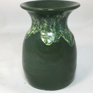 May include: A dark green ceramic vase with a flared rim. The vase has a rounded body and a contrasting light green and yellow glaze around the rim. The vase is suitable for displaying flowers or as a decorative item.