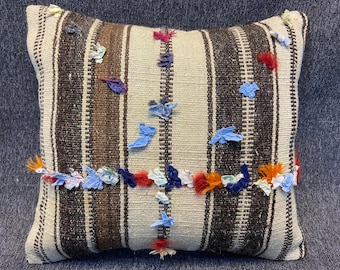May include: A decorative pillow with a striped pattern in brown and white. The pillow is adorned with colorful fabric scraps in shades of blue, red, and orange.