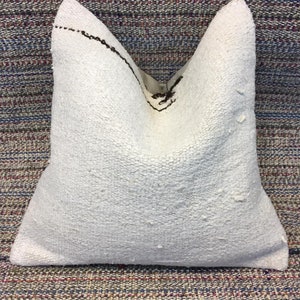May include: White throw pillow with a brown embroidered design. The pillow is made of a soft, textured fabric.
