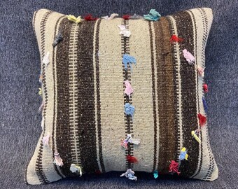 May include: A decorative throw pillow with a striped pattern in brown and white. The pillow is covered in small colorful fabric scraps, creating a unique and textured look.