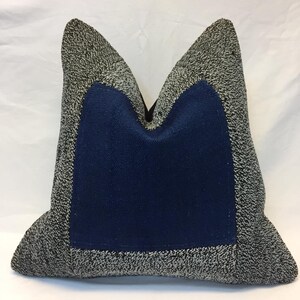 Puede incluir: Una almohada decorativa con una tela estampada en blanco y negro y un inserto de tela azul. La almohada tiene la forma de una almohada tradicional con una parte superior puntiaguda y una parte inferior plana.