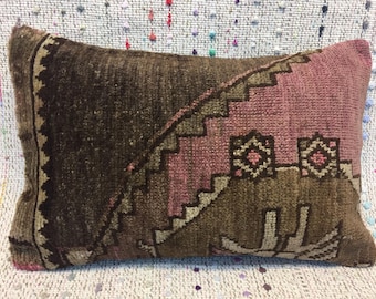 May include: A rectangular pillow with a brown and pink geometric pattern. The pillow is made of a woven fabric with a fringe border.