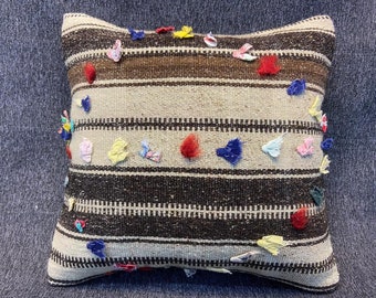 May include: A brown and white striped throw pillow with colorful fabric scraps sewn on. The pillow is made of a woven fabric and has a fringed edge.