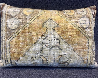 Può includere: Un cuscino rettangolare con un motivo geometrico beige e marrone. Il cuscino ha un aspetto sbiadito e vintage.