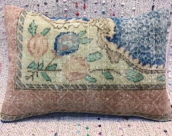 May include: A decorative pillow with a floral pattern in shades of blue, green, and pink. The pillow has a brown border and is made of a soft, woven fabric.