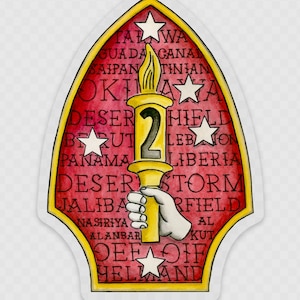 May include: A red and gold sticker featuring a torch and the number 2. The sticker includes the text "DESERT SHIELD" and "DESERT STORM", alongside a list of locations such as "GUADA CANAL", "SAIPAN", "TINIAN", "BEIRUT", "PANAMA", "LIBERIA", "JALIBAA", "NASIRIYA", "ALANBAR", "KUT", "HELLAND".