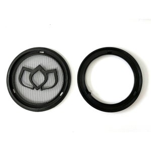 May include: Two black circular objects. One has a fine mesh screen with a floral design in the center. The other is a plain black ring. Both objects are made of a hard plastic material.