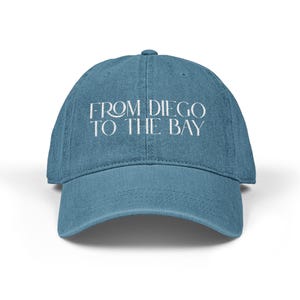 May include: A blue baseball cap with the text "FROM DIEGO TO THE BAY" in white, centered on the front. The cap has a curved brim and a structured crown. The hat is a solid, light blue color.