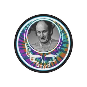 Puede incluir: Un parche redondo con borde negro. Presenta una imagen en blanco y negro de un hombre rodeado por un diseño de calavera tie-dye blanco. La calavera tiene un patrón tie-dye con colores morado, azul, naranja y amarillo.