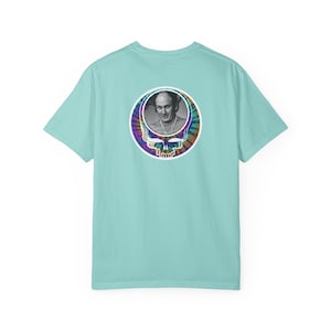 May include: A light blue t-shirt featuring a circular graphic on the back. The graphic is a tie-dye skull with a black and white portrait of a man in the center. The shirt is made of a soft material.